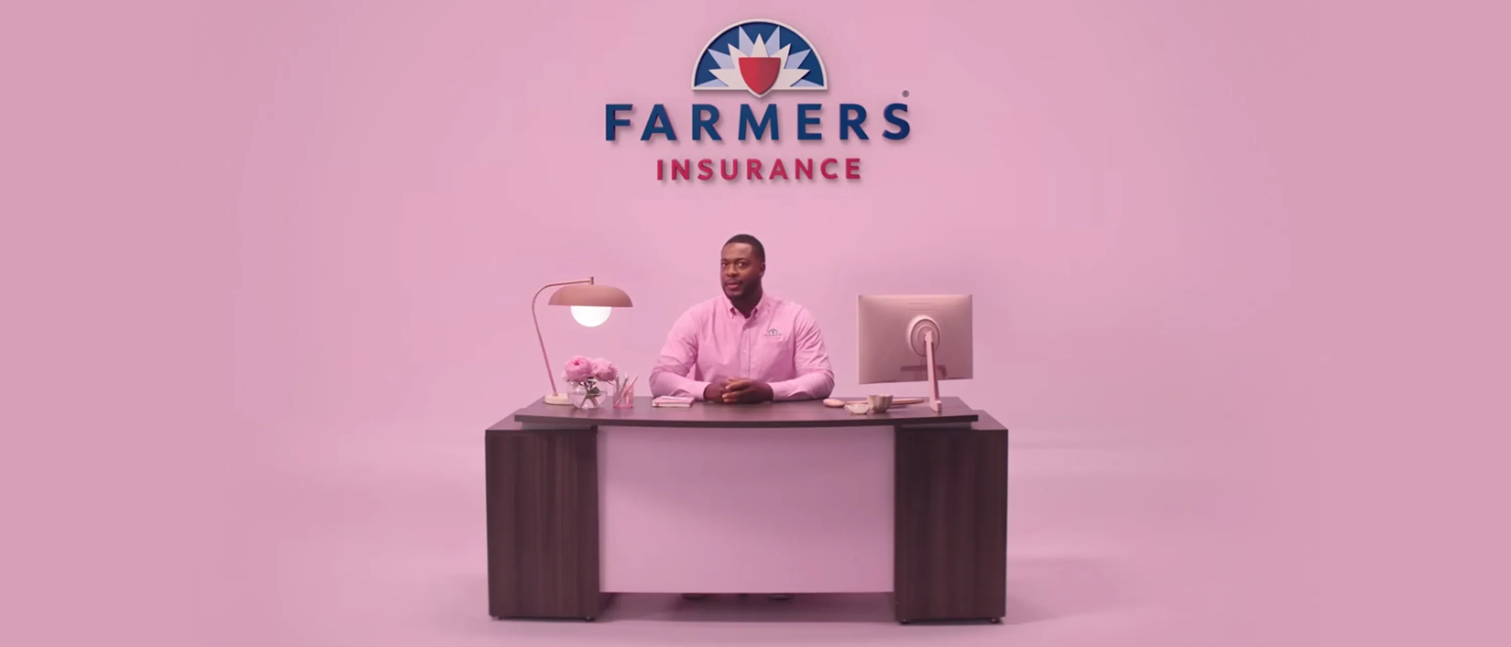 Men sitting in a desk, with the Farmers Insurance logo in pink background